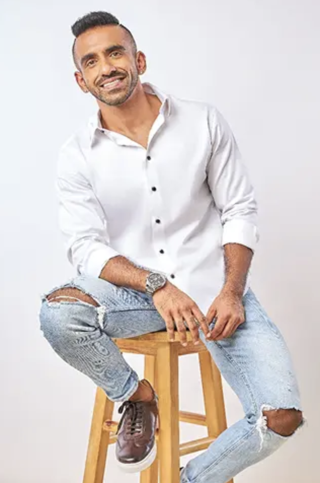 Avi smiling in a studio portrait